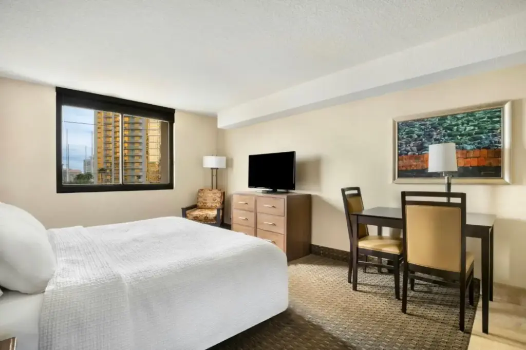 a hotel room with a bed and a desk and a television at The Carriage House in Las Vegas