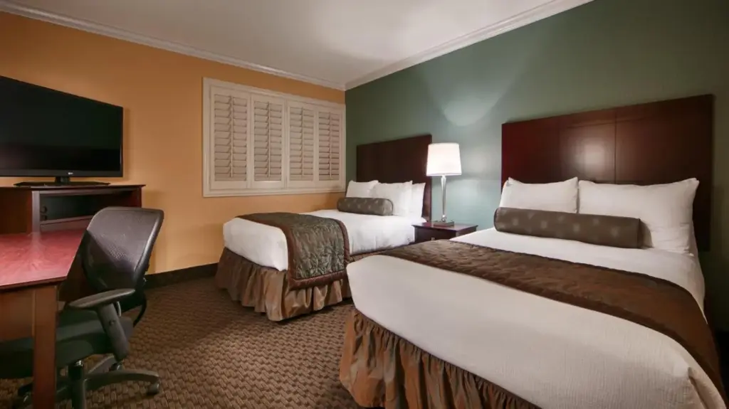 a hotel room with two beds and a desk at Best Western Plus Casino Royale–Center Strip in Las Vegas