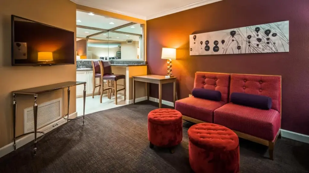 a living room with a red couch and a bar at Best Western Plus Casino Royale–Center Strip in Las Vegas