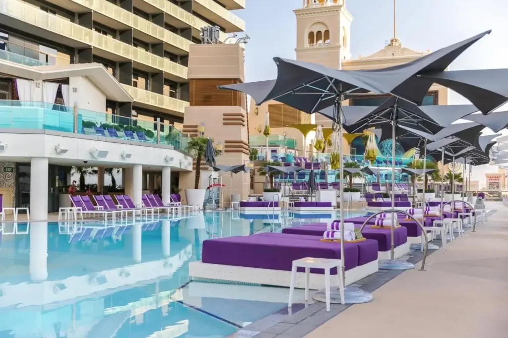 a hotel pool with purple chairs and umbrellas at The Cosmopolitan Of Las Vegas in Las Vegas