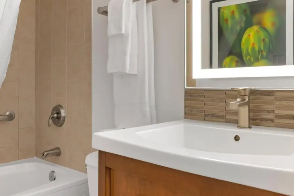 a bathroom with a white sink and a bath tub at Desert Rose Resort in Las Vegas