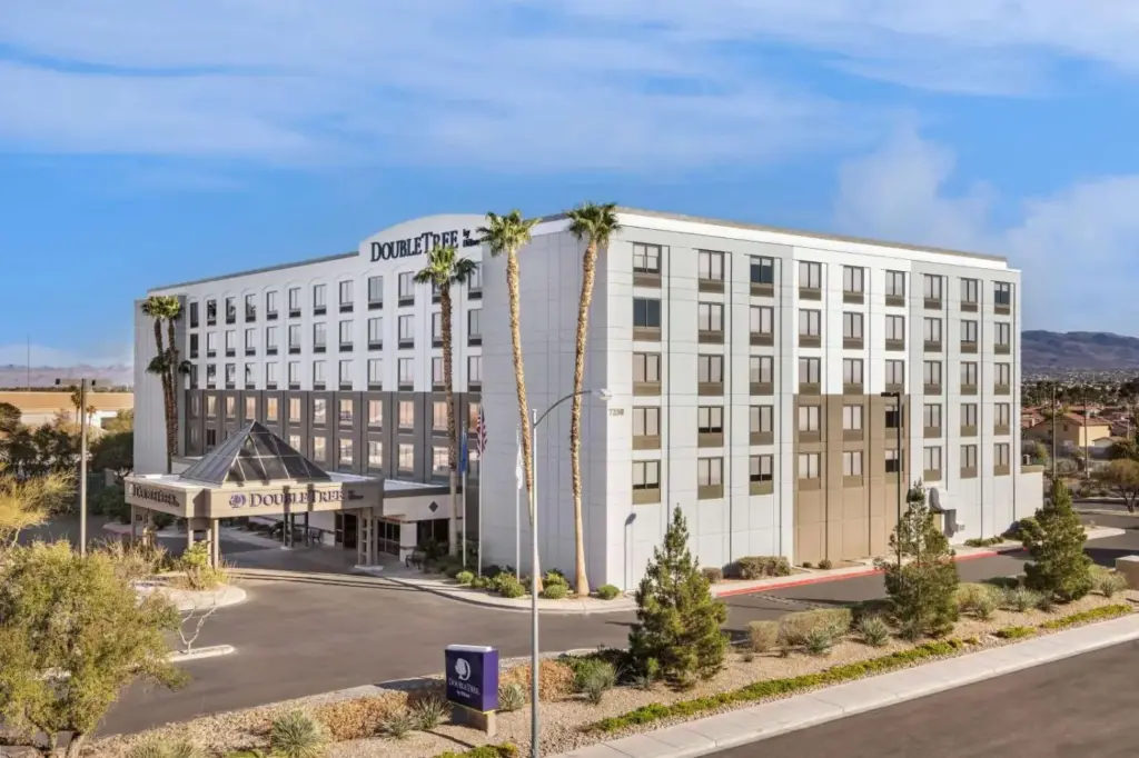 a large white building with palm trees in front of a street at DoubleTree by Hilton Las Vegas Airport in Las Vegas