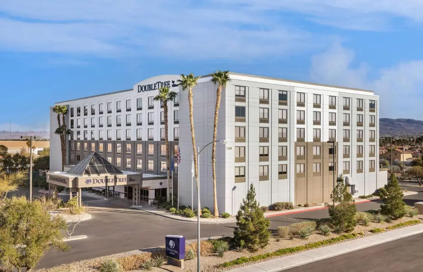 a large white building with palm trees in front of a street at DoubleTree by Hilton Las Vegas Airport in Las Vegas