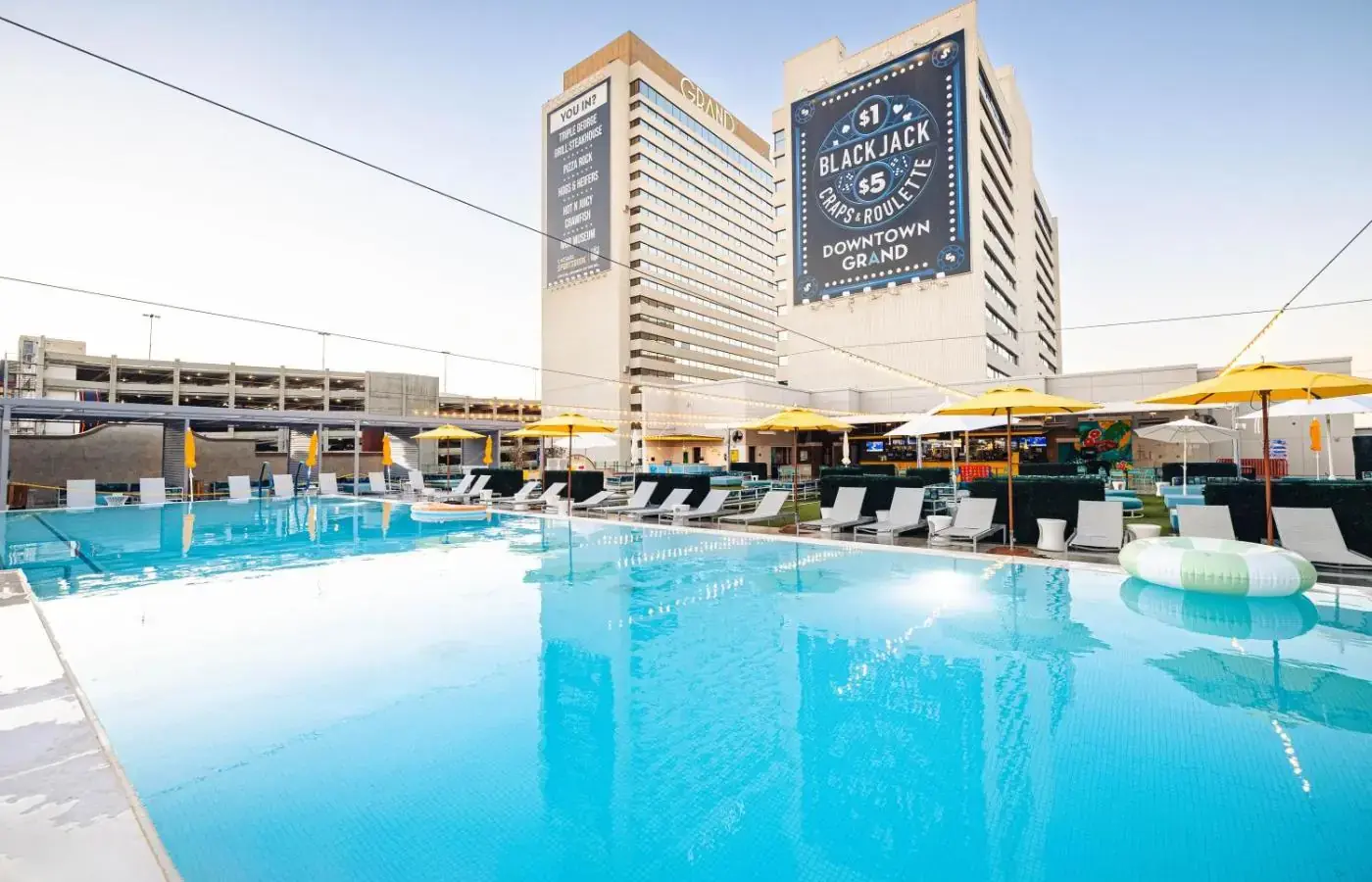 a large pool with chairs and umbrellas in front of a hotel at Downtown Grand Hotel & Casino in Las Vegas