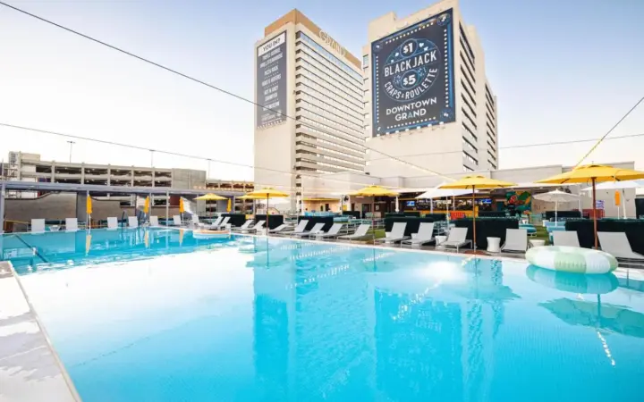 a large pool with chairs and umbrellas in front of a hotel at Downtown Grand Hotel & Casino in Las Vegas
