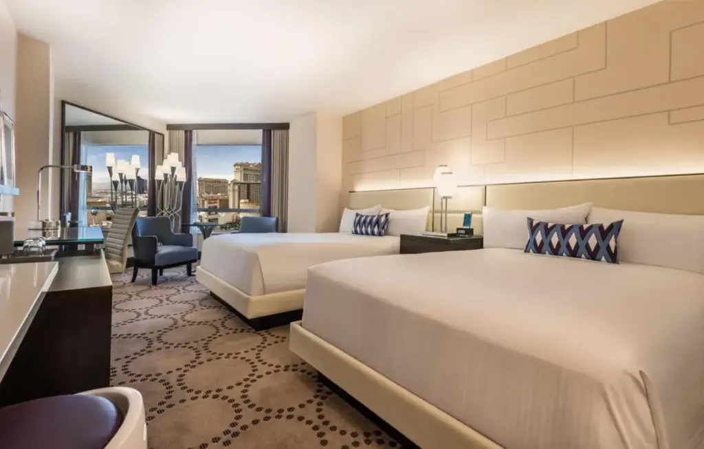 a hotel room with two beds and a desk at Harrah's Las Vegas, A Caesars Destination in Las Vegas