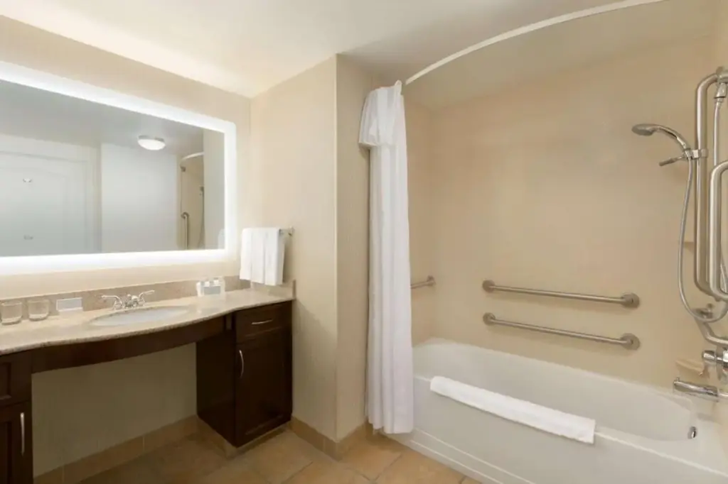 a bathroom with a tub and a sink and a mirror at Homewood Suites by Hilton Las Vegas Airport in Las Vegas