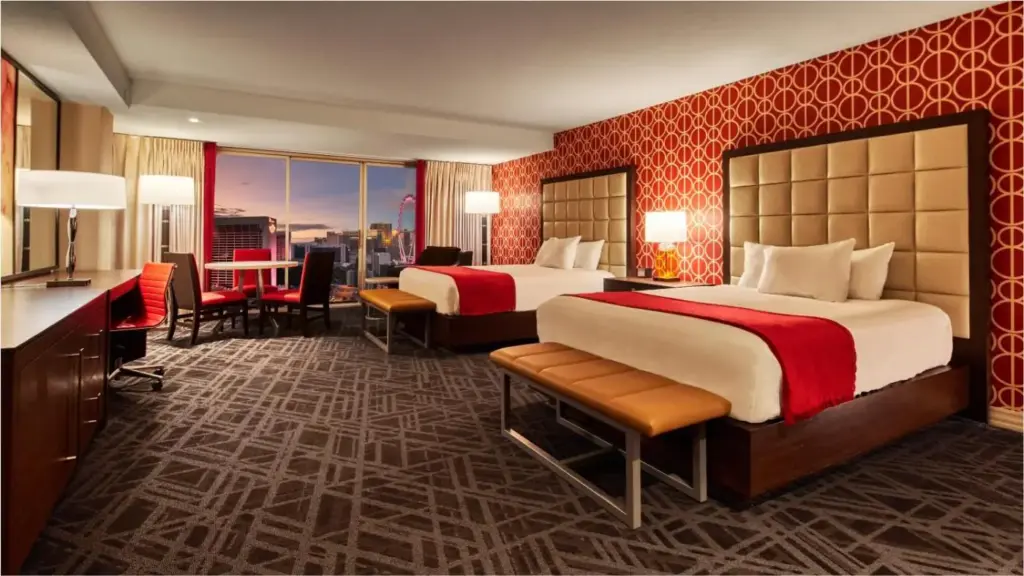 a hotel room with two beds and a desk and a kitchen at Horseshoe Las Vegas Hotel & Casino - A Caesars Rewards Destination in Las Vegas