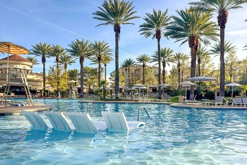 a swimming pool with white chairs and palm trees at JW Marriott Las Vegas Resort & Spa in Las Vegas