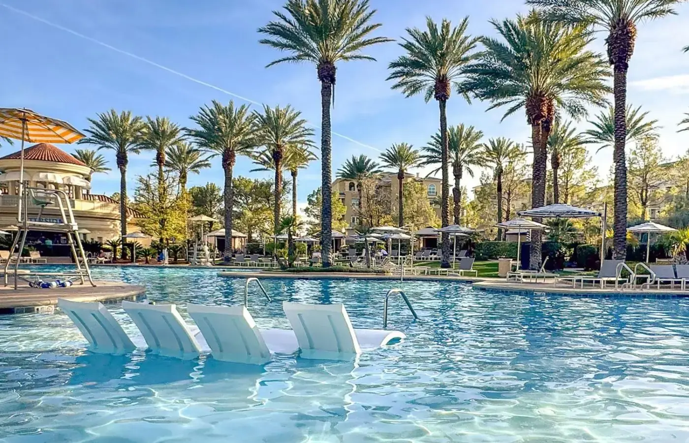 a swimming pool with white chairs and palm trees at JW Marriott Las Vegas Resort & Spa in Las Vegas