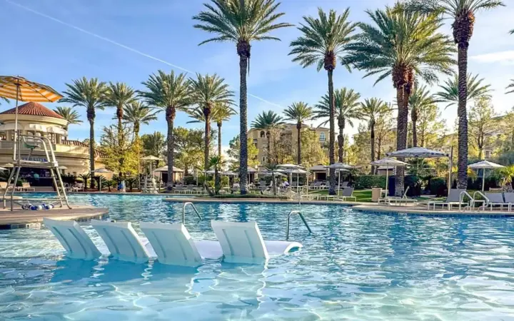 a swimming pool with white chairs and palm trees at JW Marriott Las Vegas Resort & Spa in Las Vegas
