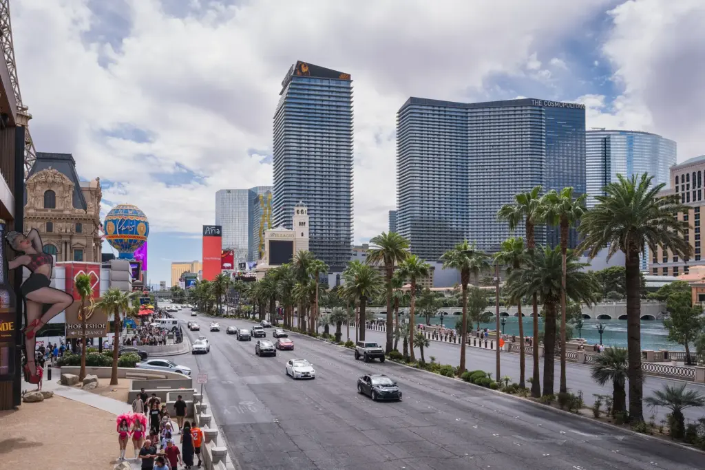 People walking on the Las Vegas Strip sidewalk with The Cosmopolitan towers ahead