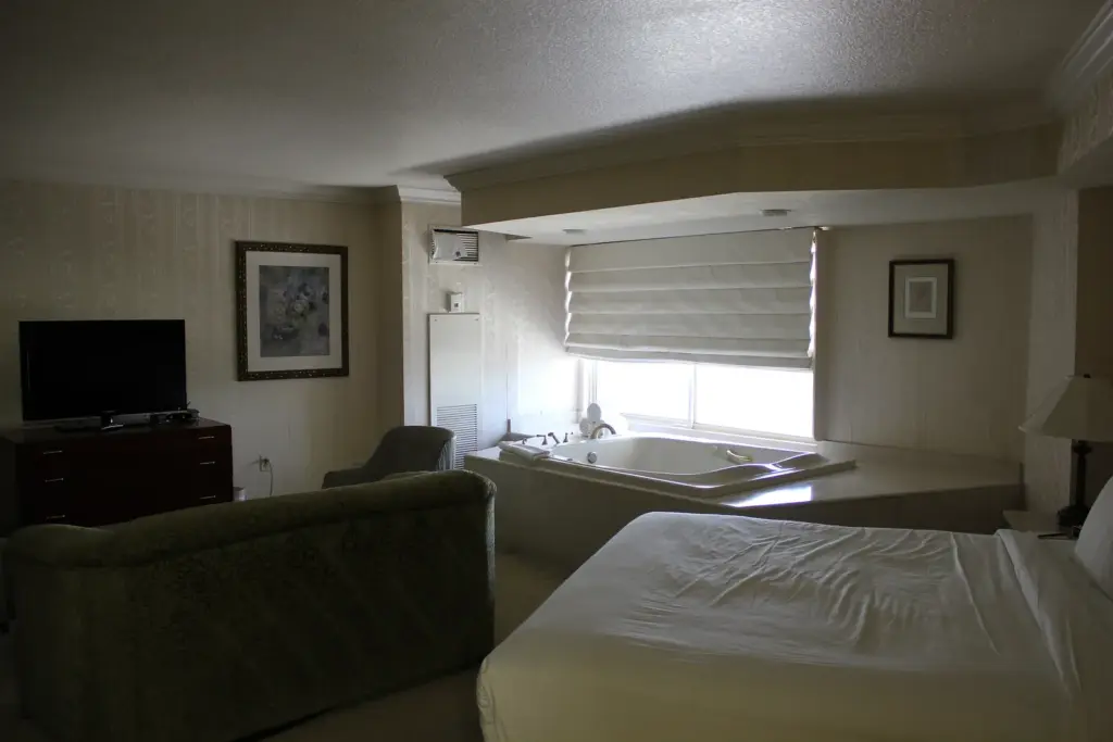 Las Vegas hotel suite with a jetted spa tub by the window next to the bed