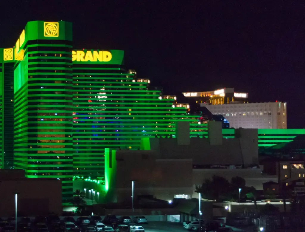La torre iluminada verde de MGM Grand por la noche, con las torres de oro de Mandalay Bay en la distancia