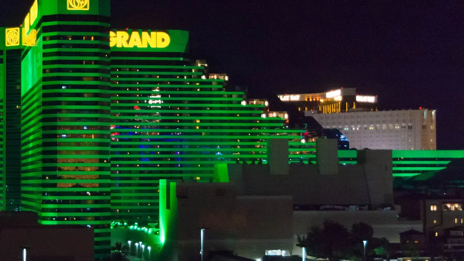 MGM Grand's green-lit tower at night, with Mandalay Bay's gold towers in the distance