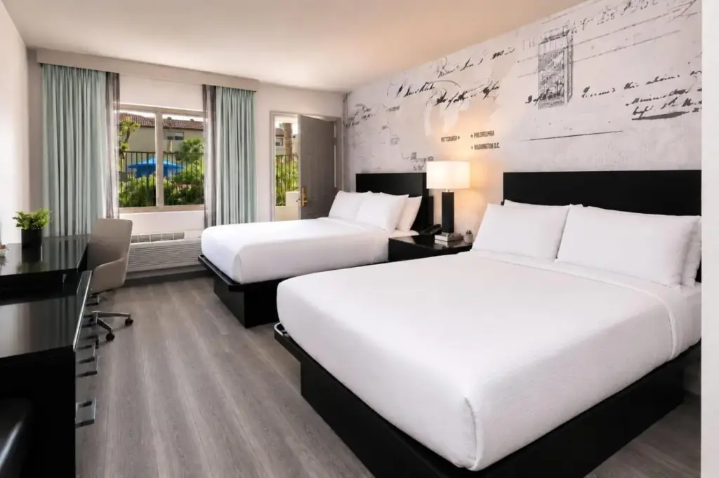 a hotel room with two beds and a desk at Silver Sevens Hotel and Casino, a Wyndham Garden in Las Vegas