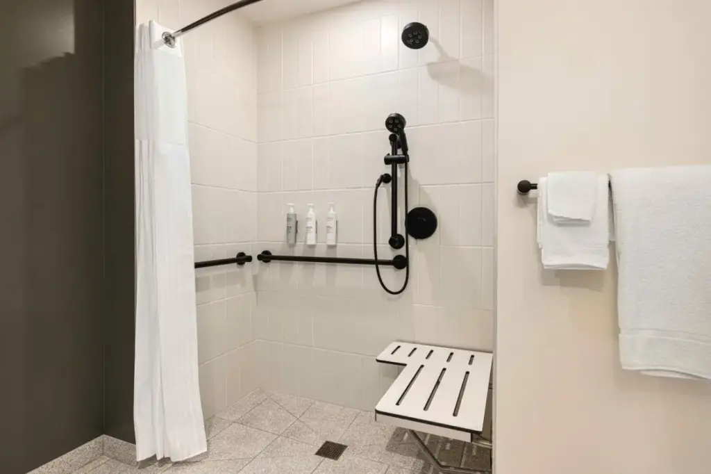 a white shower with a bench in a bathroom at Spark By Hilton Las Vegas Airport in Las Vegas