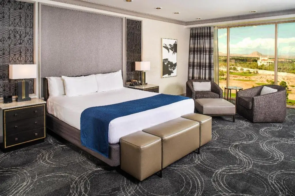 a hotel room with a large bed and a chair at Suncoast Hotel and Casino in Las Vegas