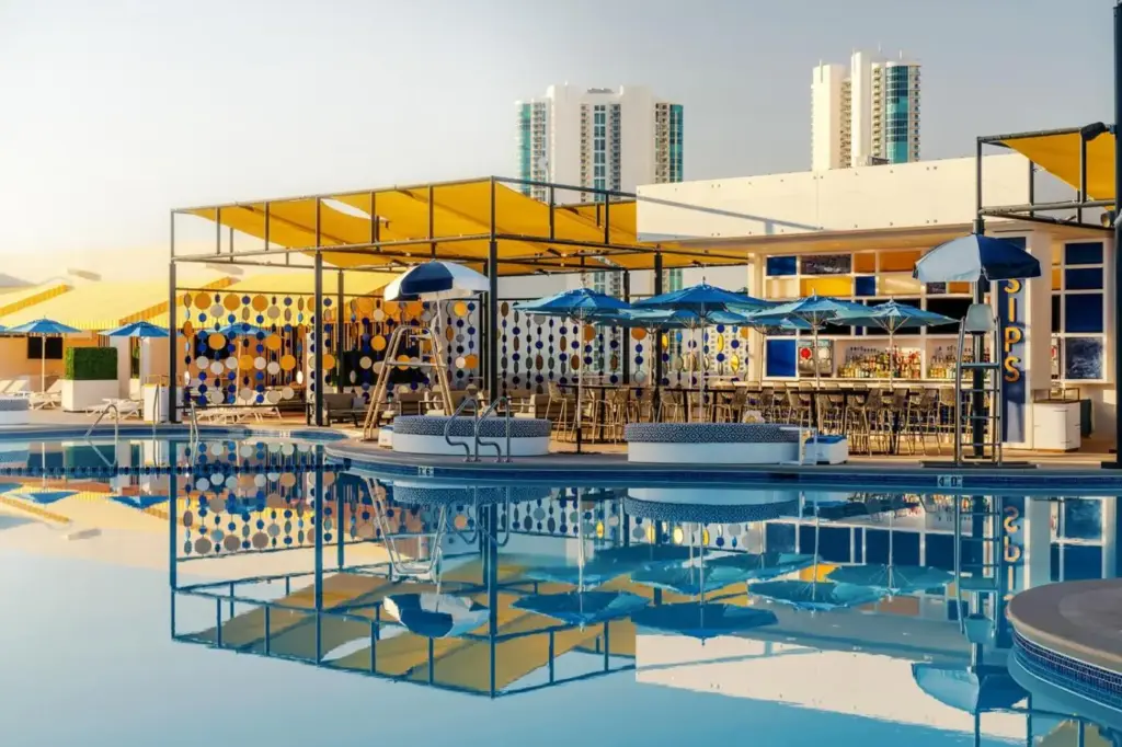 a pool with tables and umbrellas and a building at The STRAT Hotel, Casino & Tower in Las Vegas
