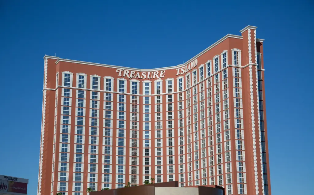 Treasure Island hotel tower with its name against a deep blue sky