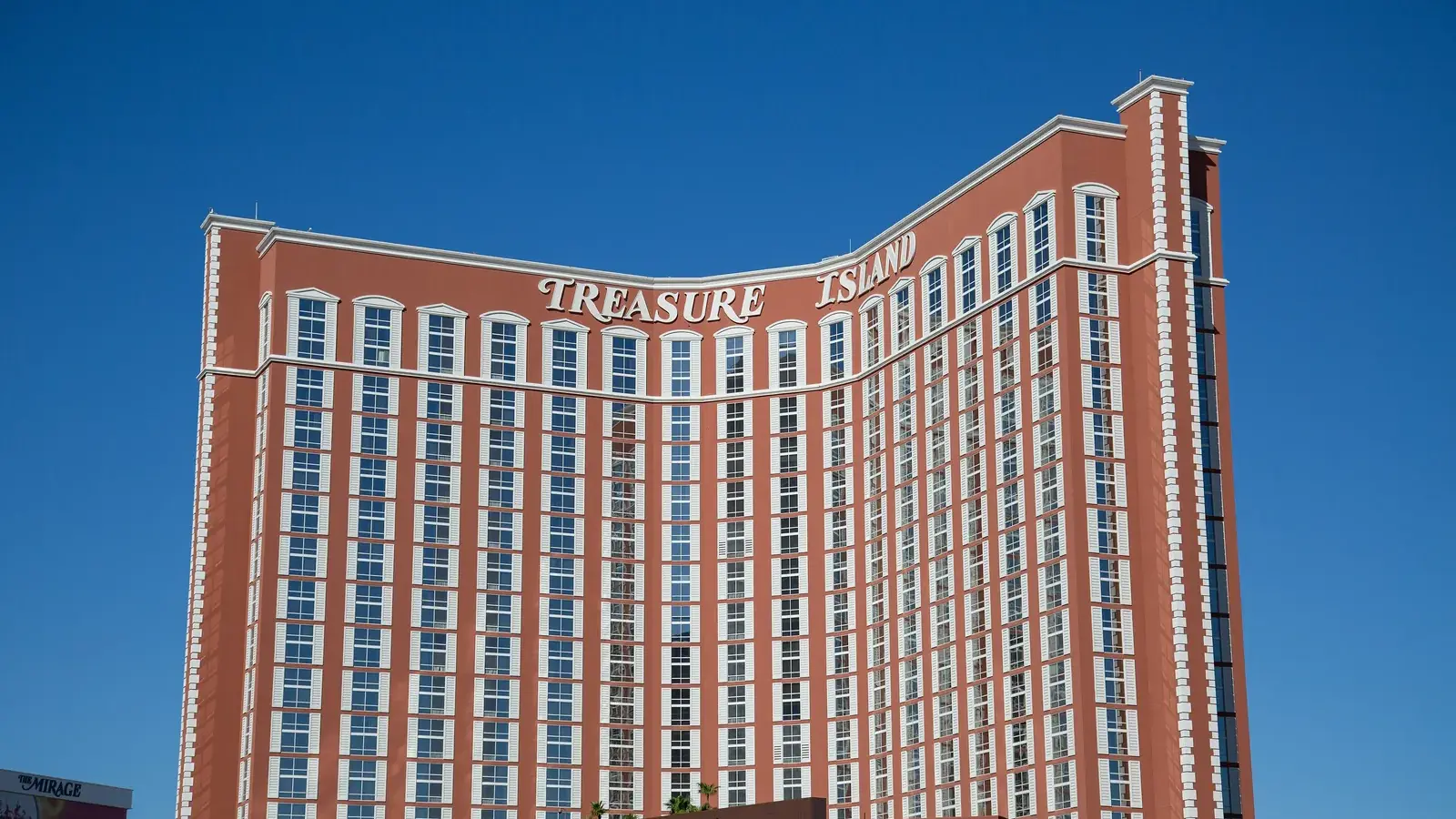 Treasure Island hotel tower with its name against a deep blue sky