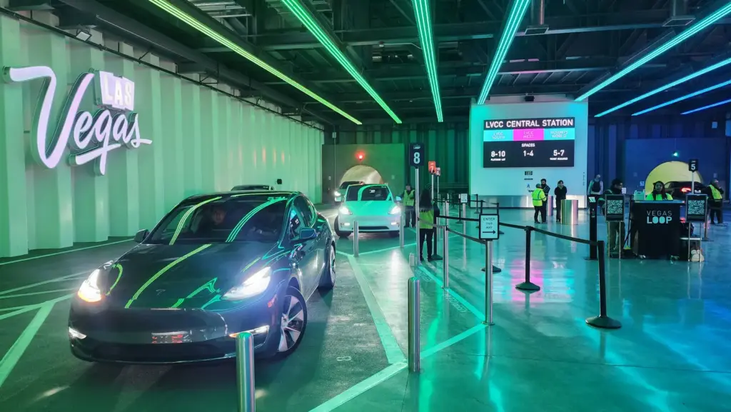 Tesla waiting at the LVCC Central Station of the Vegas Loop under neon lights